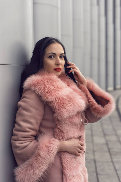 Brunette in the city in a pink coat - Photo, image