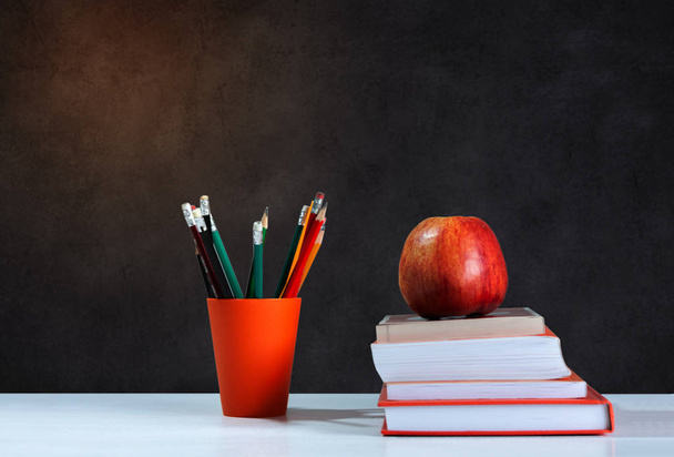 Back to school, orange pencil holder, stack of books on white ta - Photo, image