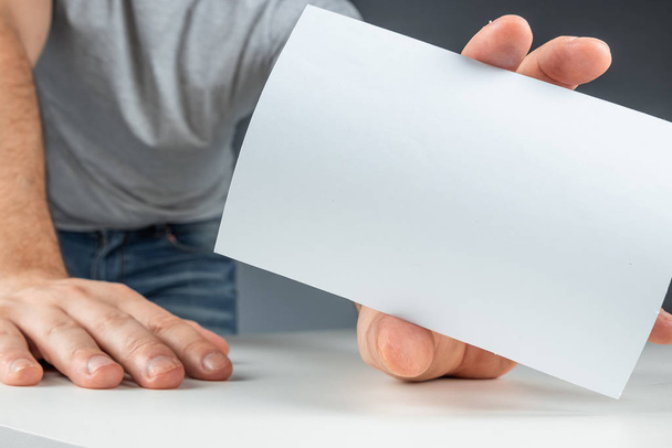 Close-up male hand holds a white card, mockup, layout, copy space. - Foto, imagen
