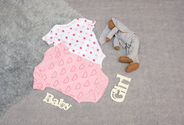 Bodysuits, Kleidung für ein neugeborenes Mädchen.auf grauem Hintergrund mit  - Foto, Bild