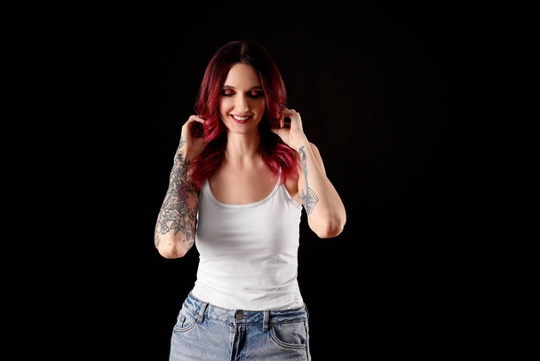 Beautiful woman with tattoos on arms against black background - Foto, Imagen