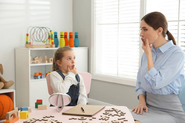 Speech therapist working with little girl in office - Photo, image