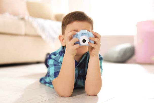 Little photographer taking picture with toy camera at home - Фото, изображение