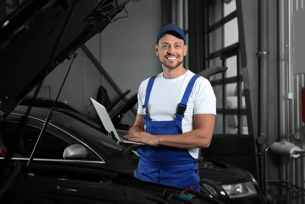 Mechanic with laptop doing car diagnostic at automobile repair s - Foto, afbeelding