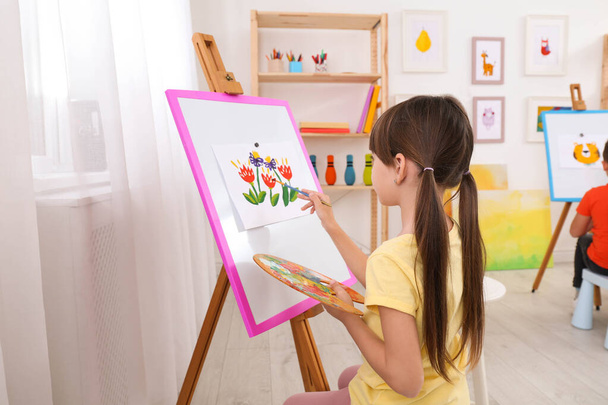 Cute little child painting during lesson in room - Фото, изображение