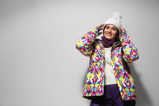 Woman wearing stylish winter sport clothes on light grey backgro - Фото, изображение