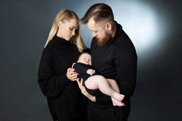 Man and a woman hold a baby in their arms. Portrait of a married - Fotoğraf, Görsel