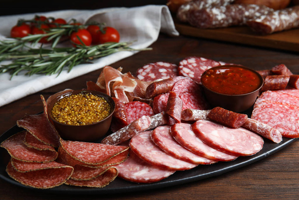 Different types of sausages with sauce served on wooden table - Foto, afbeelding