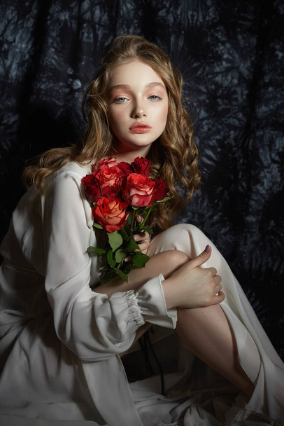 Beautiful spring girl is sitting on the floor with rose flowers  - Fotoğraf, Görsel