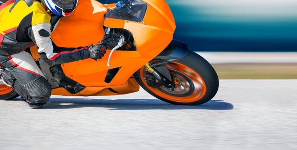 Мотоцикл нахиляється в швидкий кут на гоночній трасі
 - Фото, зображення