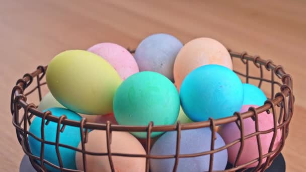 Young woman is preparing for Easter egg hunting, setting decorated colored colorful eggs in a little bamboo basket in home kitchen, close up, lifestyle, 4K. - Materiał filmowy, wideo