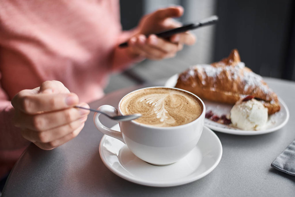 Femme prendre le petit déjeuner en caffe et en utilisant un smartphone. fille chattin
 - Photo, image