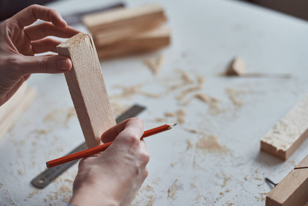 Carpenter hands taking measurement with a pencil of wooden plank. Concept of DIY woodwork and furniture making - 写真・画像