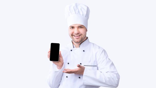 Шеф-повар ресторана показывает мобильный телефон с пустым экраном на белом фоне
 - Фото, изображение