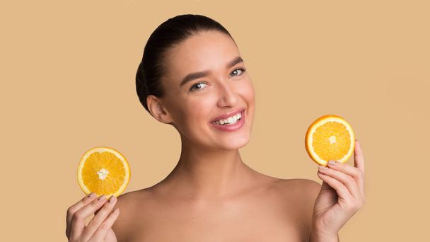 Frutas e conceito de cuidados com a pele. Mulher segurando pedaços de laranjas
 - Foto, Imagem