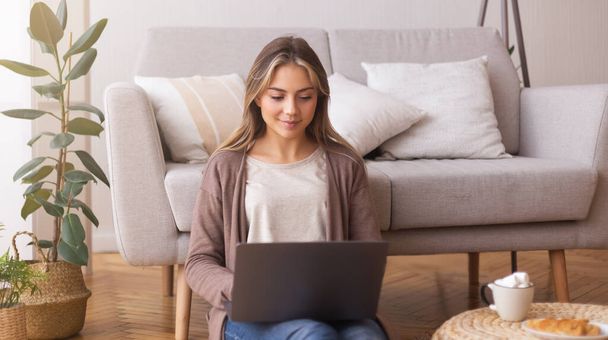 Młoda kobieta przeglądająca na laptopie w domu - Zdjęcie, obraz