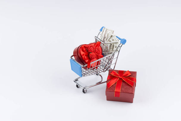 Shopping cart with presents, flowers and moneys on white background - Foto, immagini
