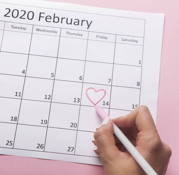 Woman painting heart on Date February 14 on calendar - Φωτογραφία, εικόνα