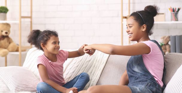 African american sisters giving fist bump to each other at home - Photo, Image