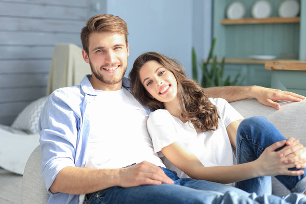 Portrait of cute young couple sitting in sofa. - Фото, изображение