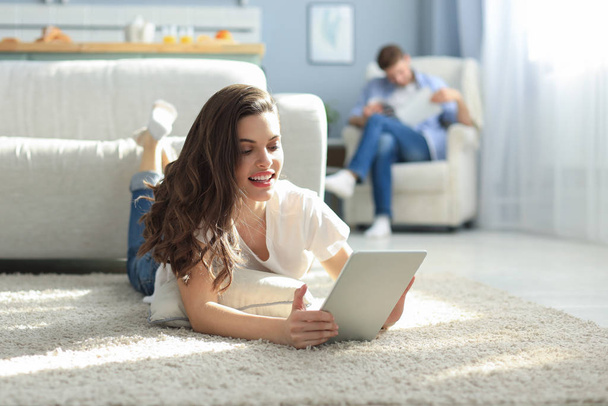Smiling beautiful woman using laptop with blurred man in background at home. - Foto, Imagem
