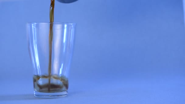 schwarzer Kaffee, der in ein transparentes Glas auf einem isolierten blauen Hintergrund gegossen wird - Filmmaterial, Video