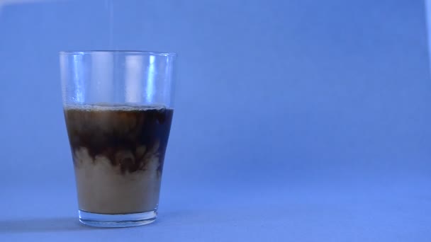 in a glass with black coffee add milk on a blue background with place for text - Video