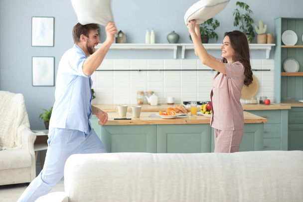 Happy loving couple having fun while having a pillow fight in the living room. - Foto, Imagem