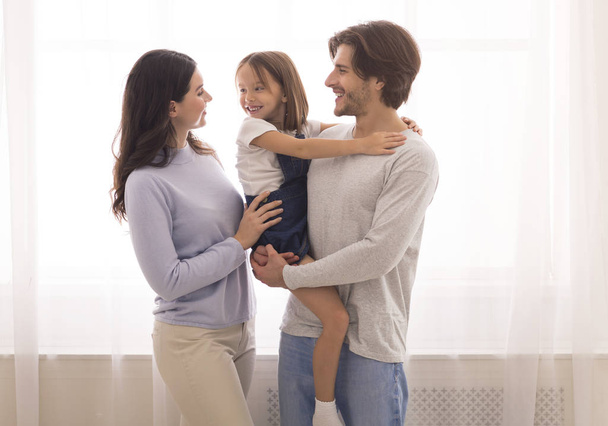 Familia feliz de tres abrazando y uniéndose en casa
 - Foto, Imagen