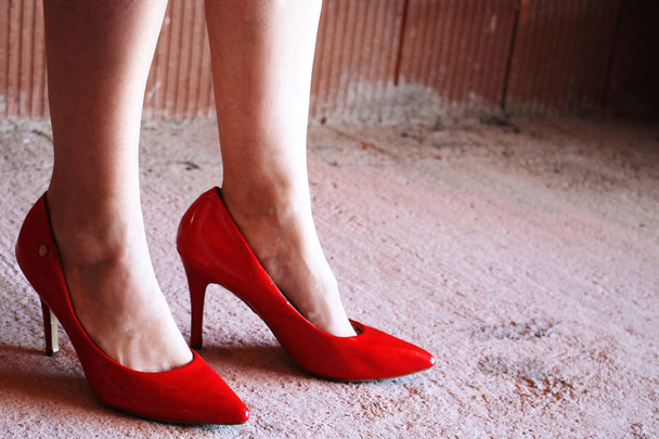 γυναικεία πόδια με κόκκινα παπούτσια φτέρνα σε ένα ημιτελές σπίτι - Φωτογραφία, εικόνα