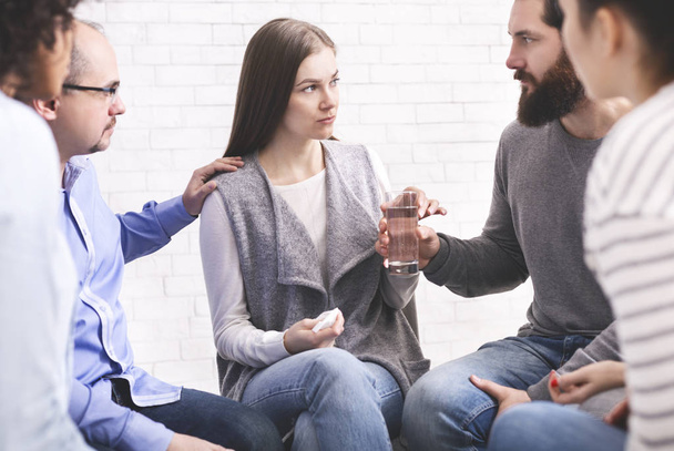 Therapy group members comforting upset woman at community meeting in rehab - Photo, Image