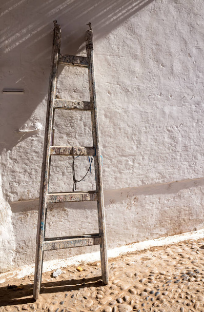 Old wooden ladder and a wall in sunlight - Fotoğraf, Görsel