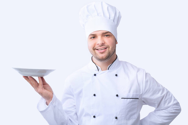 Chef sosteniendo placa vacía posando en estudio sobre fondo blanco
 - Foto, imagen