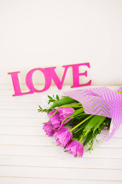 boeket paarse tulpen op witte tafel, houten liefdesbrieven, close-up - Foto, afbeelding