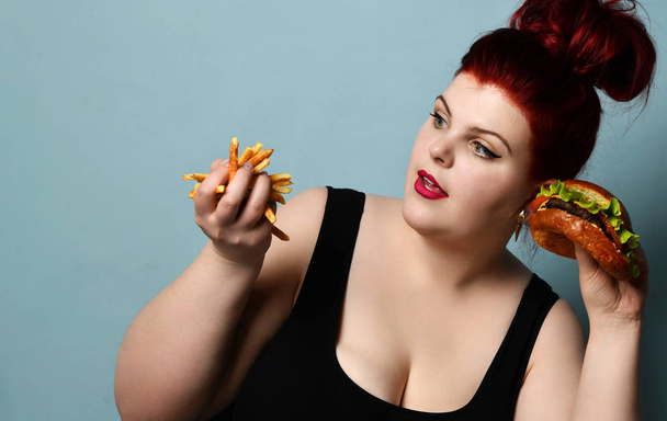 Happy overweight fat woman happy hold burger cheeseburger sandwich with beef and french fries in hand - Photo, image