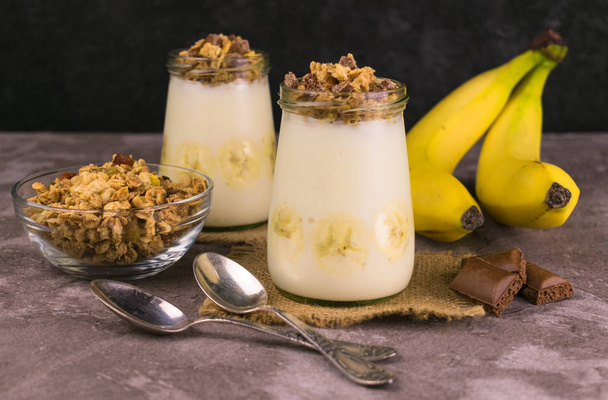 Granola with yogurt, chocolate and banana on a gray background. Granola, healthy breakfast. - Zdjęcie, obraz