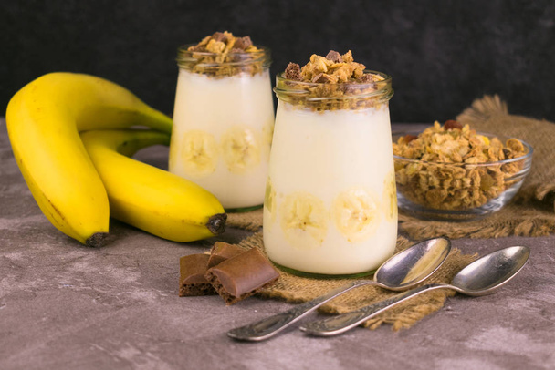 Dolce morbido a base di yogurt alla banana e muesli su fondo scuro. Dolci utili
. - Foto, immagini