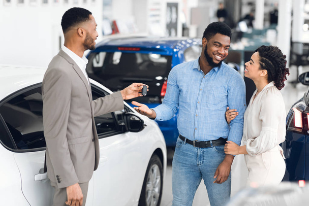 Family Buying Auto Taking Key From Car Dealer In Store - 写真・画像