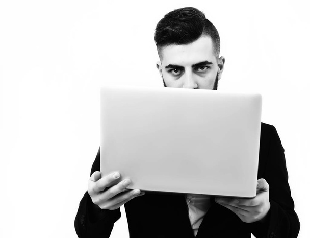 Successful businessman with serious look holds white laptop - Фото, изображение