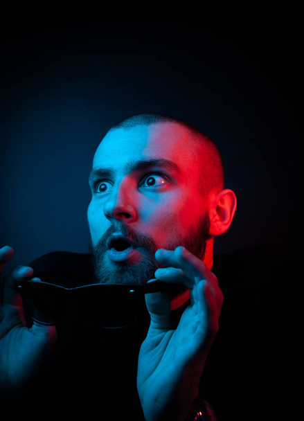 Studio portrait of a charismatic guy in neon style. Stock photo of a bearded guy surprised by surprise. - Photo, Image