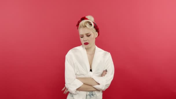 Escéptico pin up mujer posando con los brazos cruzados sobre fondo rosa
 - Metraje, vídeo
