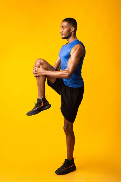 Молодой черный спортсмен ходит высоко держа колено
 - Фото, изображение