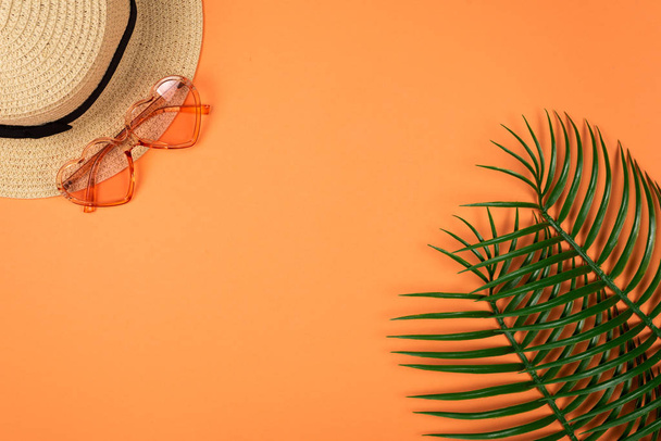 Roze zonnebril en een hoed op oranje achtergrond.  - Foto, afbeelding