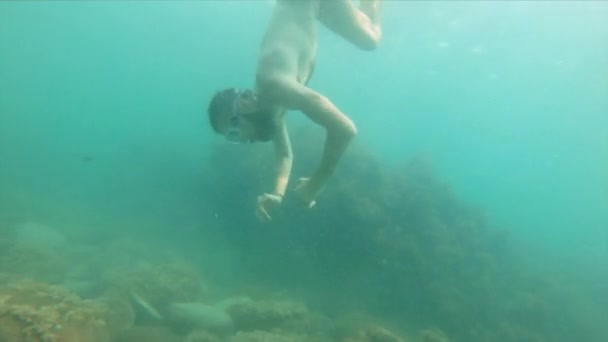 Egy vékony, álarcos szakállas férfi úszik a víz alatt, integet a karjával. Közelkép. - Felvétel, videó