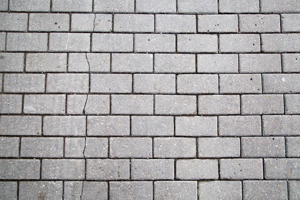 Background of gray artificial paving stones of rectangular shape with a crack on the sidewalk. Backgrounds, textures, interior. - Foto, Imagen
