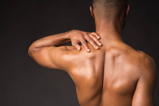 Черный мужчина без рубашки делает массаж шеи и плеч
 - Фото, изображение