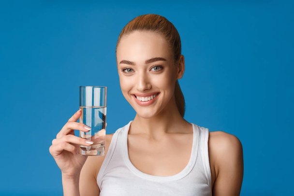 Nő kezében pohár víz mosolygó álló kék háttér - Fotó, kép