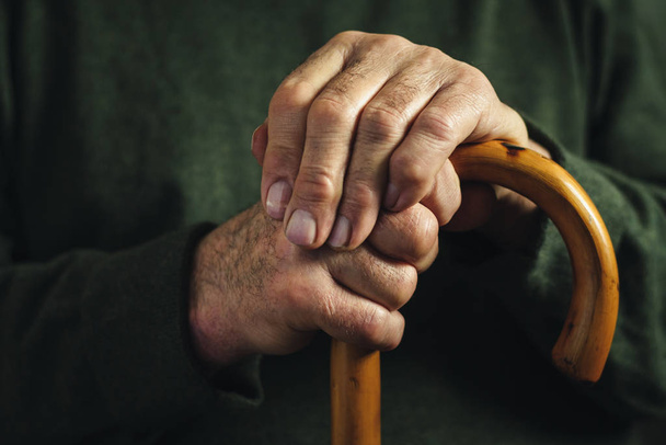 Hombre discapacitado mayor sujetando su bastón
 - Foto, imagen