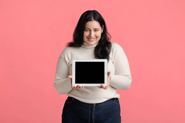 Девушка счастливого размера плюс демонстрации цифровой планшет с черным пустым экраном
 - Фото, изображение