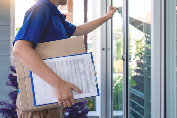 Entrega hombre en azul uniforme entrega caja de paquete para el signo del cliente
 - Foto, imagen